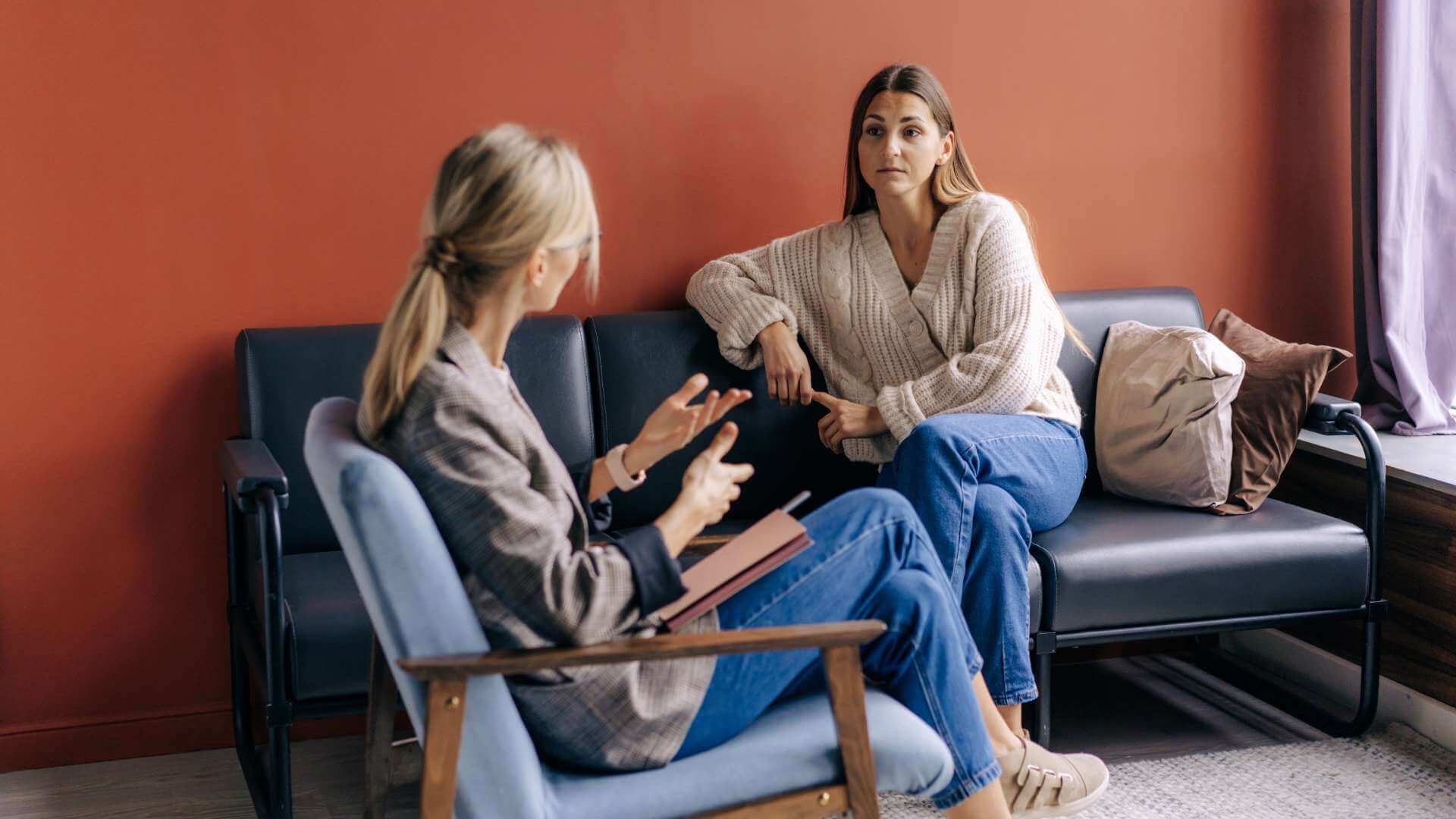 Two women are deeply engaged in conversation while seated on a couch.