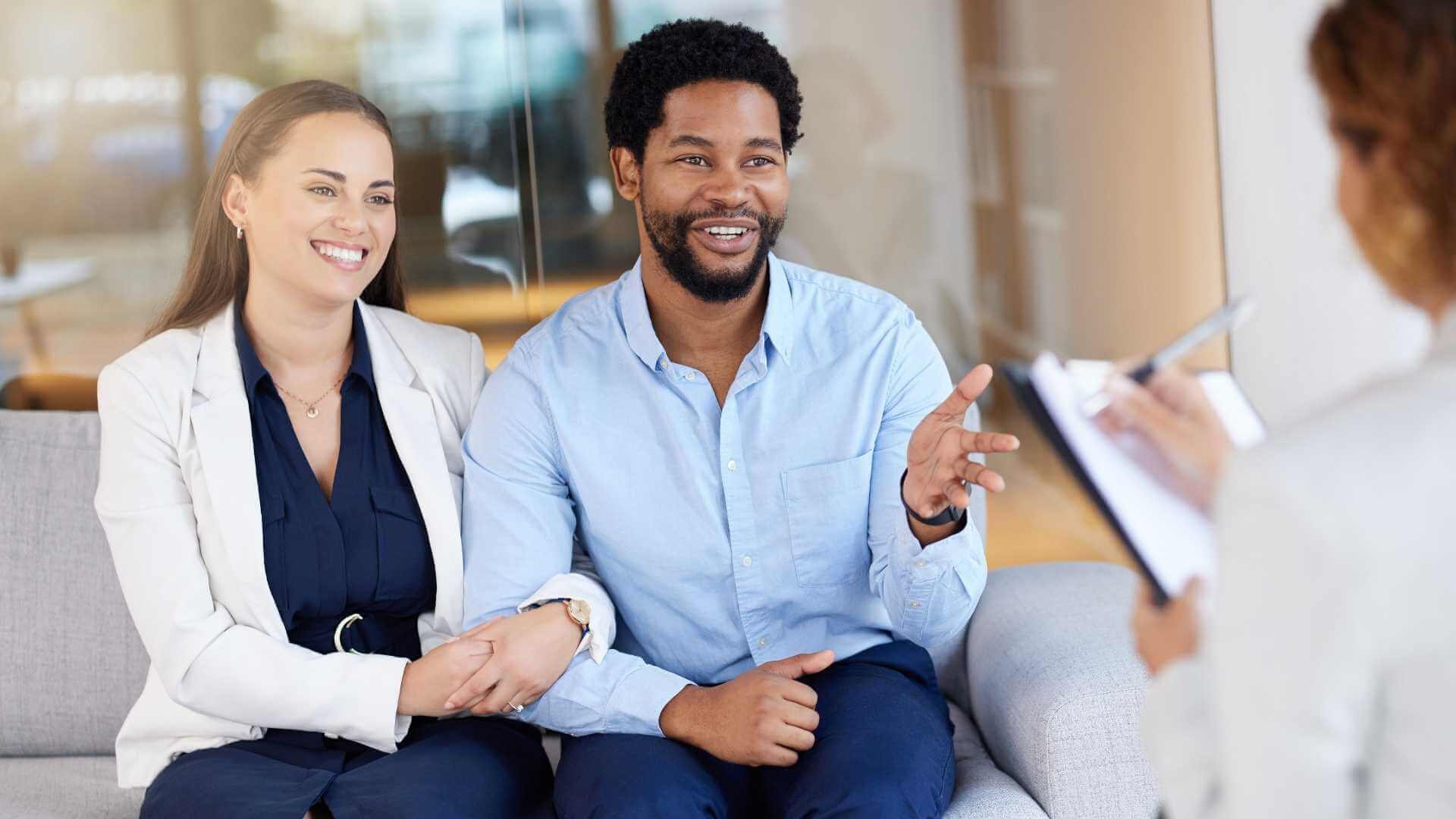 A man and woman chatting with a lady on a couch.