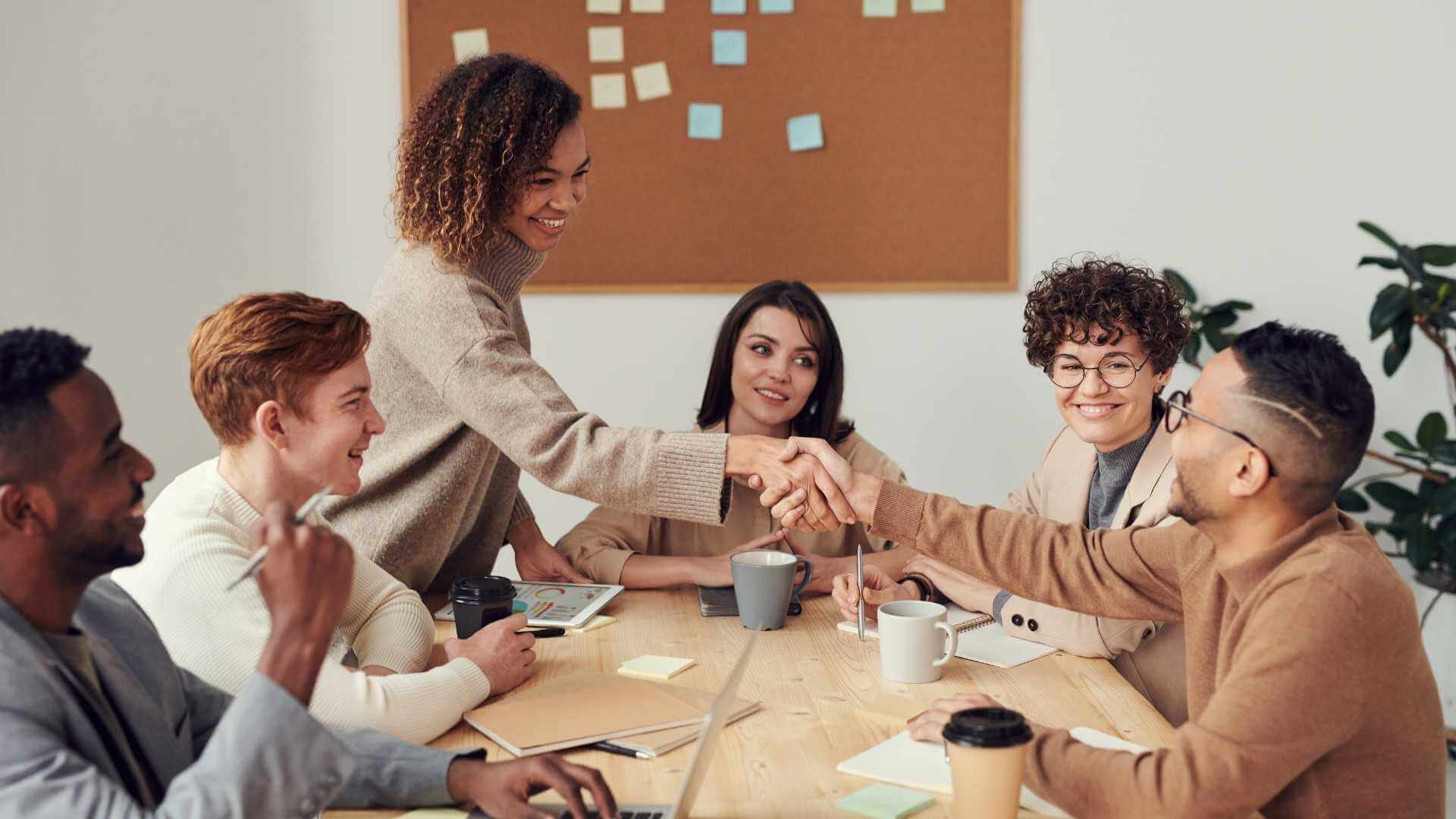 A group of people shaking hands at a meeting.