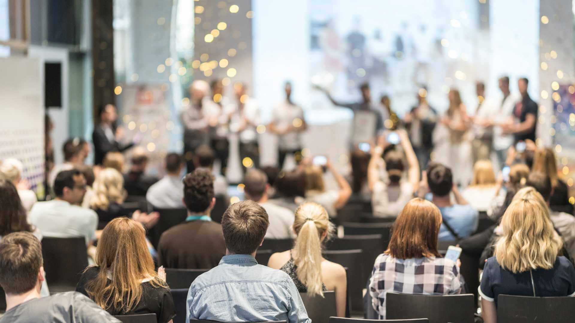 A crowded conference room with many people gathered for a meeting.