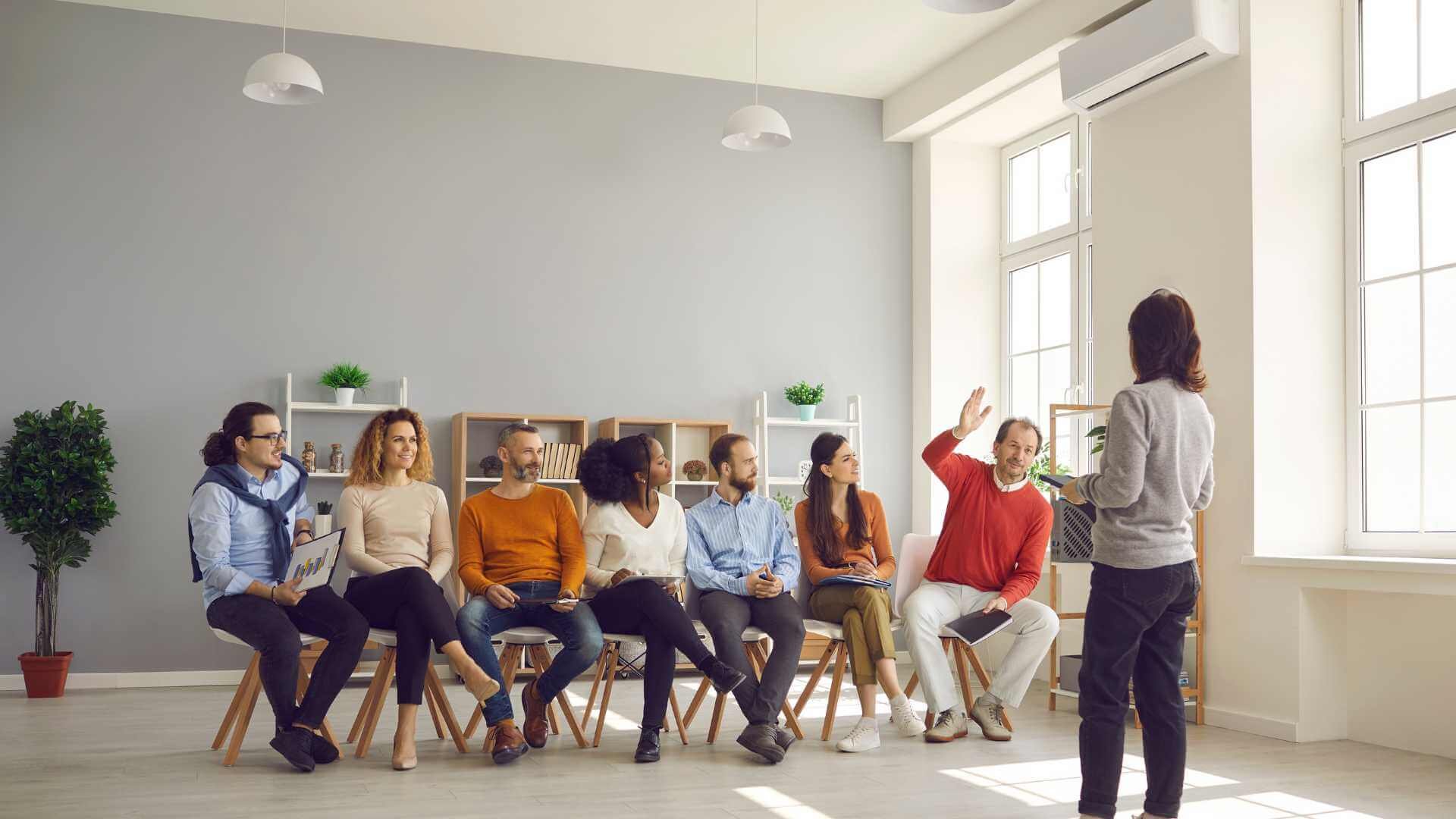 A woman standing in front of a group of people sitting in a room.